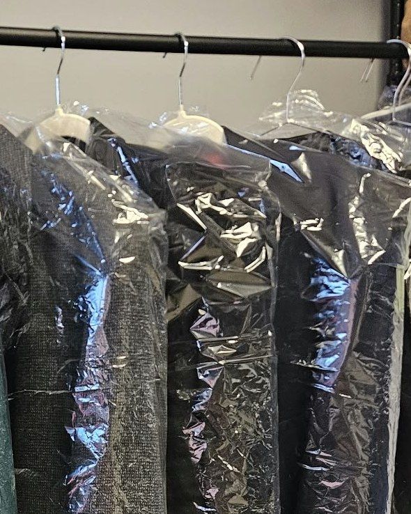 Pressed jackets in protective covers on the rail at North Coast Laundry, ready for collection